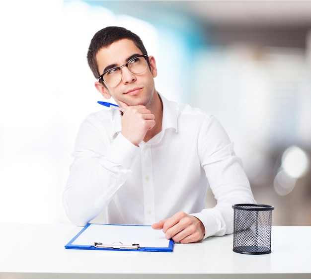 Pensive man with a ball-point pen and check table