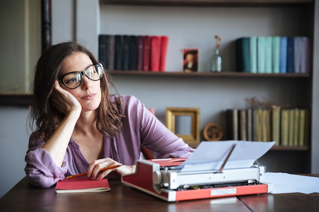 Pensive mature authoress in eyeglasses thinking and looking away