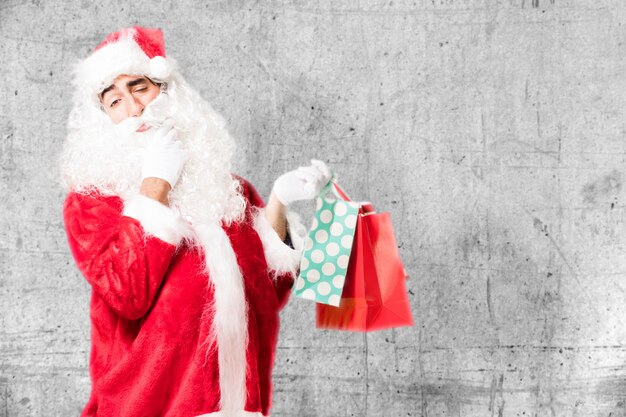 Free Photo pensive santa claus holding shopping bags