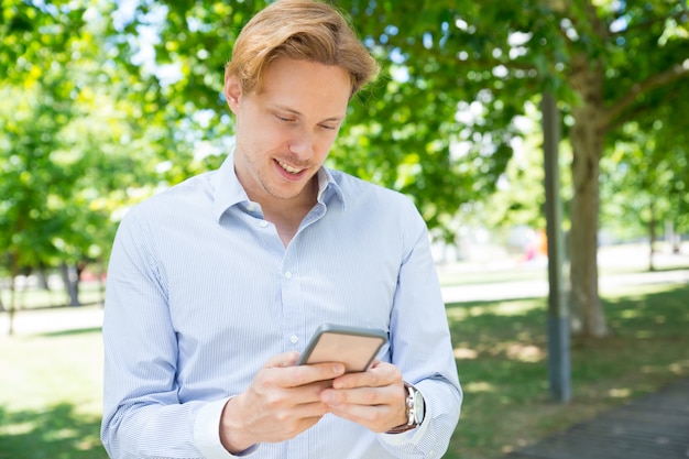 Free Photo pensive smiling guy texting message on phone