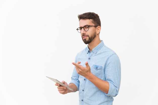 Pensive tablet user looking and pointing finger away