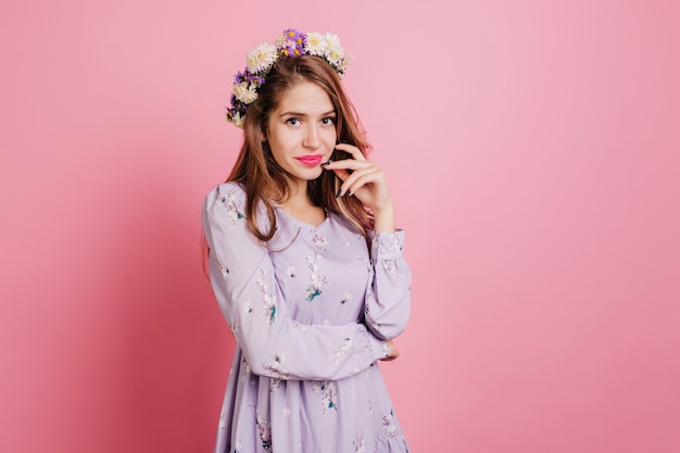 Free photo pensive woman in flower wreath posing on pink wall