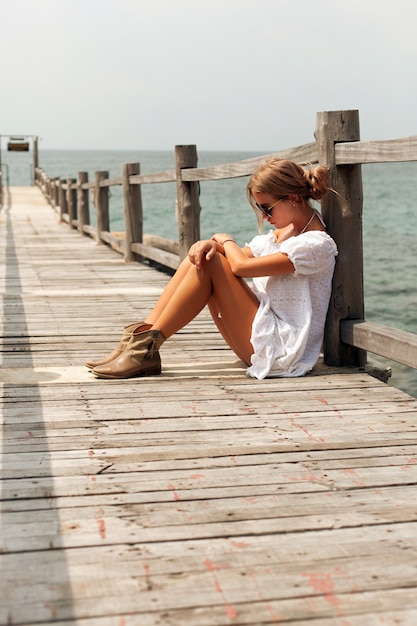 Pensive woman sitting on a pier