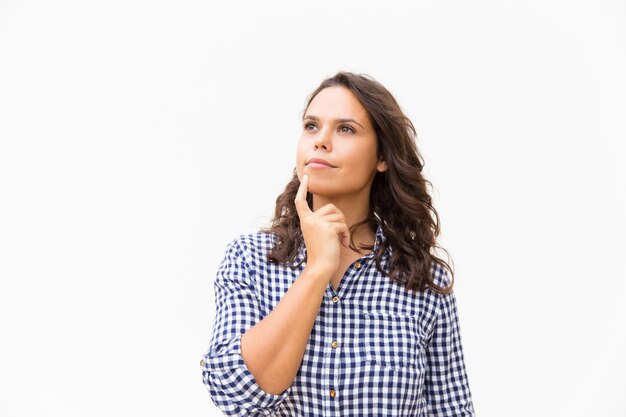 Pensive woman touching chin and looking away