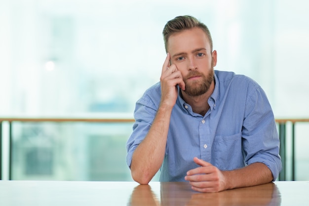 Pensive Young Man Sitting at Empty Cafe Table