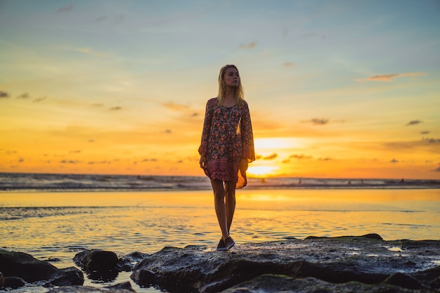 people on the beach at sunset. the girl is jumping against the backdrop of the setting sun.