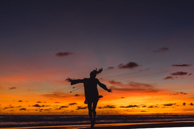 Free photo people on the beach at sunset. the girl is jumping against the backdrop of the setting sun.