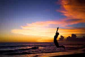 Free photo people on the beach at sunset. the girl is jumping