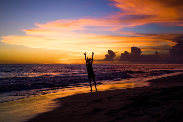 Free photo people on the beach at sunset. the girl is jumping