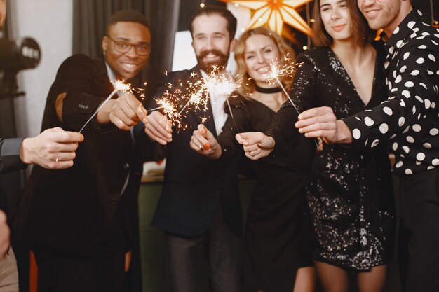 People in a Christman decorations. Man in a black suit. Group celebrations New Year. People with bengal lights.