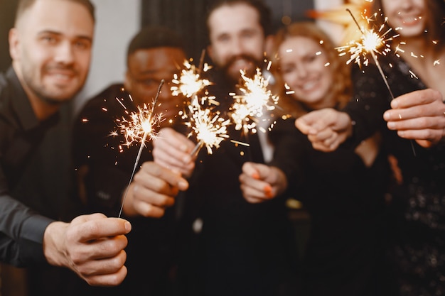 Free Photo people in a christman decorations. man in a black suit. group celebrations new year. people with bengal lights.