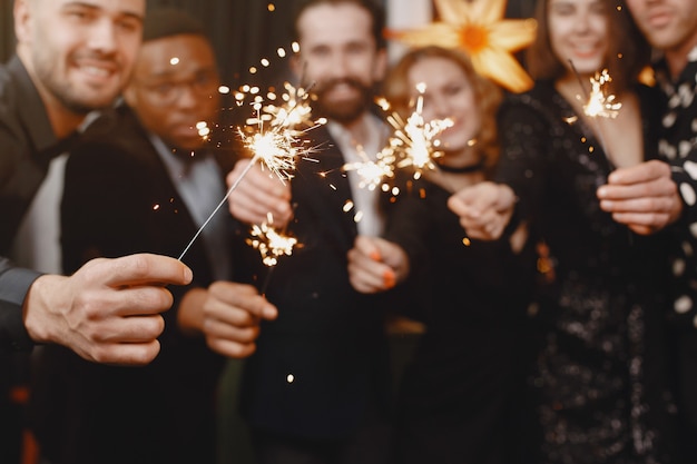 Free Photo people in a christman decorations. man in a black suit. group celebrations new year. people with bengal lights.