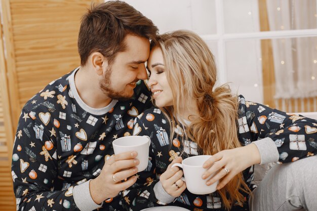 People in a Christman decorations. Man and woman in a identifical pajamas. Family on a bed.