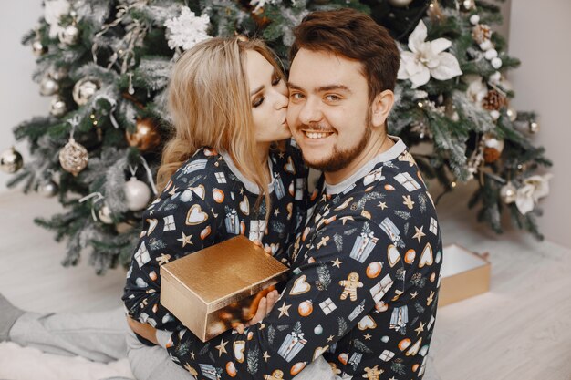 People in a Christman decorations. Man and woman in a identifical pajamas. Family at home.