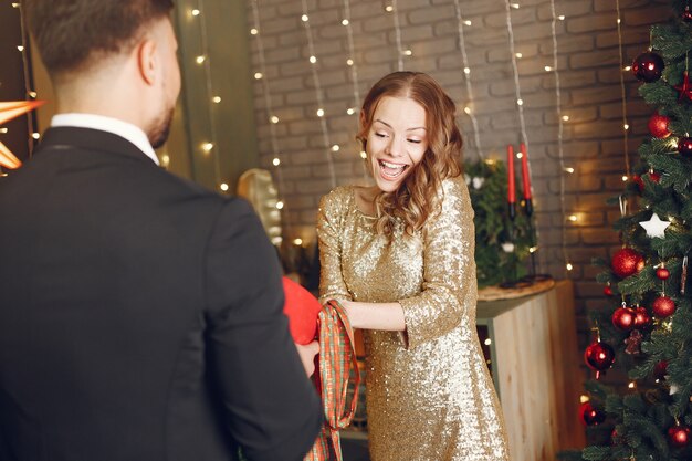 People in a Christmas decorations. Man in a black suit. Woman with red box.