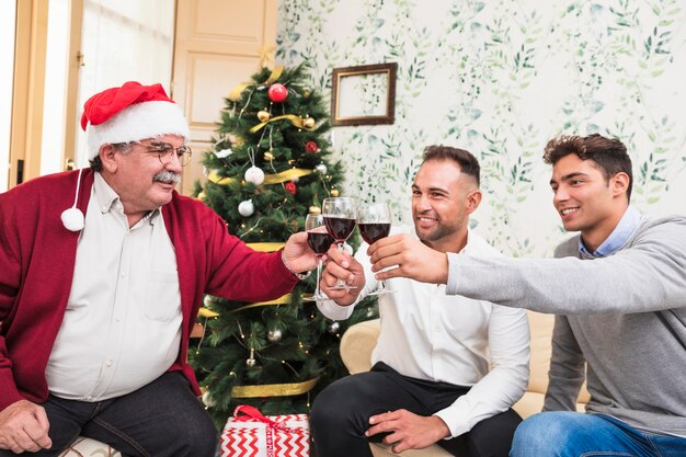 People clanging glasses near Christmas tree 