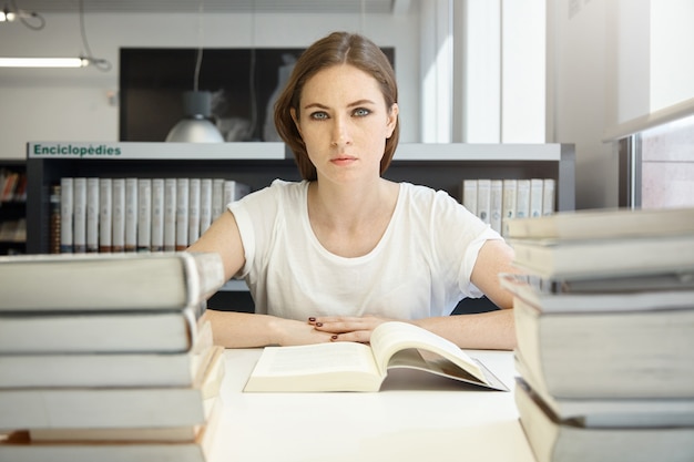 People and education concept. Tired female student studying, reading textbook on economics, preparing for MBA test or exam, feeling exhausted, sitting at desk at library