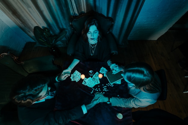 People hold hands of night at table with candles