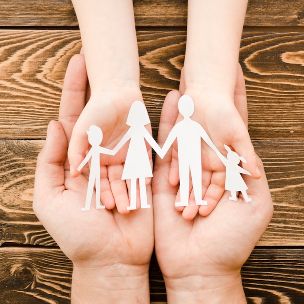 People holding paper family on wooden background