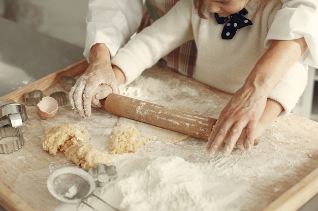 People in a kitchen. Grandmother with little daughter. Adult woman teach little girl to cook.