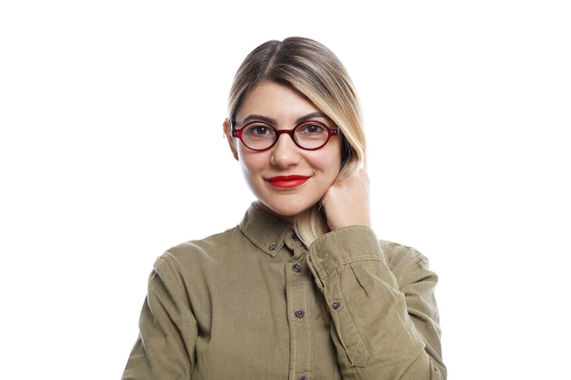 Free photo people, lifestyle, beauty, fashion and style. fashionable young european woman wearing trendy eyeglasses, red lipstick and stylish shirt posing at white wall with happy excited facial expression