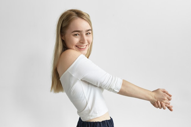 Free photo people and lifestyle concept. sideways shot of gorgeous adorable young european woman with staight blonde hair posing with arms outstretched forward, smiling broadly, feeling happy