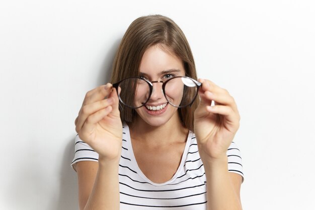 People, lifestyle, health, eyewear, optics and vision concept. Portrait of happy cheerful young woman holding stylish glasses