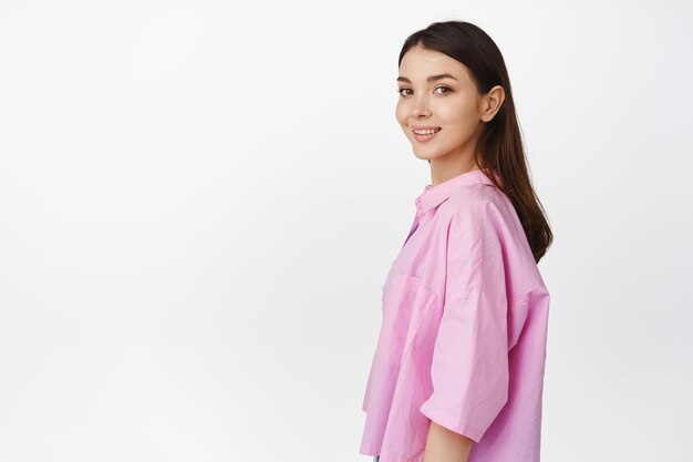 People and lifestyle Portrait of young female model turn head at camera and looking hopeful smiling standing in profile against white background