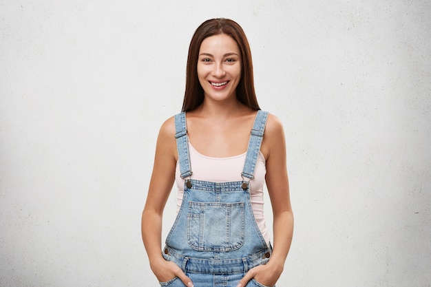 People, lifestyle, youth and happiness. Isolated portrait of gorgeous positive young lady with long dark hair and perfect clean skin smiling cheerfully