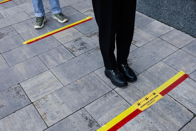 People in line waiting behind social distance stripe