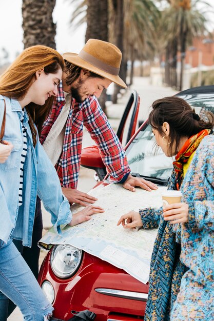 People looking at road map near red car