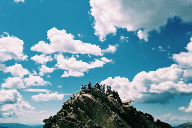 Free photo people on the peak of the mountain over the blue sky