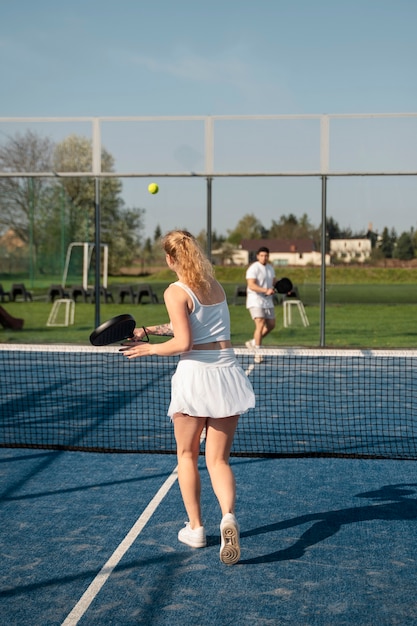 People playing paddle tennis outdoors full shot