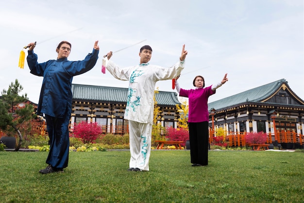 Free photo people practicing tai chi outdoors full shot