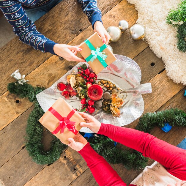 People presenting gifts at table decorated for Christmas