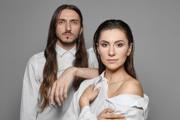 People, relationships, love and partnership concept. Isolated shot of stylish couple in white shirts posing together: handsome hipster guy with beard placing hand on woman's shoulder