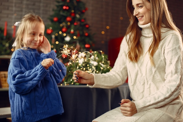 People reparing for Christmas. Kid with bengal lights. Family is resting in a festive room. Child in a blue sweater.