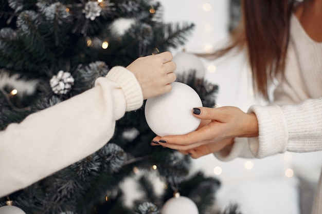 Free Photo people reparing for christmas. mother playing with her daughter. family decorated christmass tree. little girl in a white dress.