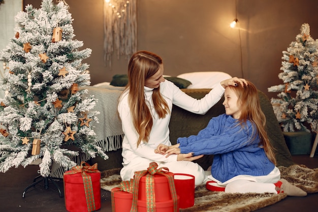 People reparing for Christmas. Mother playing with her daughter. Family is resting in a festive room. Child in a blue sweater.