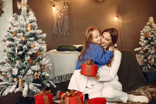 People reparing for Christmas. Mother playing with her daughter. Family is resting in a festive room. Child in a blue sweater.