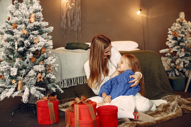 People reparing for Christmas. Mother playing with her daughter. Family is resting in a festive room. Child in a blue sweater.