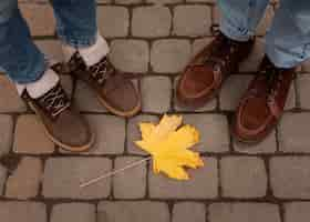 Free photo people's shoes around yellow leaf