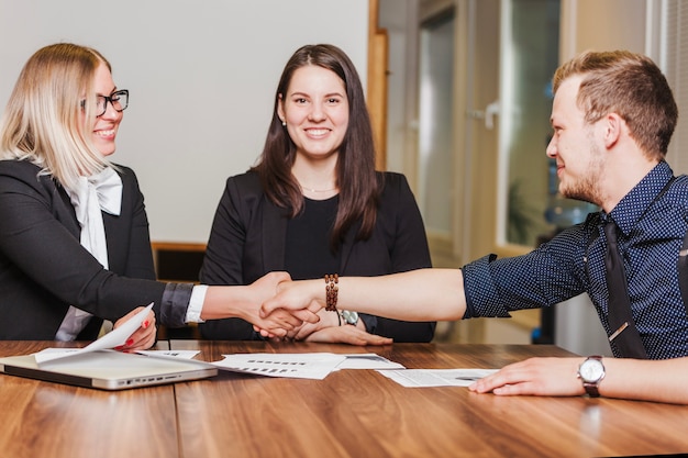 Free Photo people sitting at desk smiling shaking hands