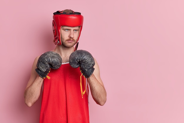 Free Photo people sport motivation concept. serious male boxer wears protective hat shirt and boxing gloves going to make punch wants to become champion.