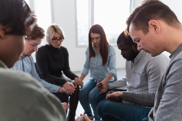 Free Photo people standing in a circle with closed eyes and holding hands