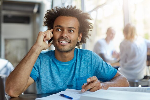 People, technology and communication concept. Handsome African American student with beard smiling, having nice phone conversation