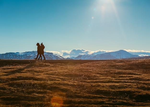 Free photo people walking in a field with beautiful snowy hills