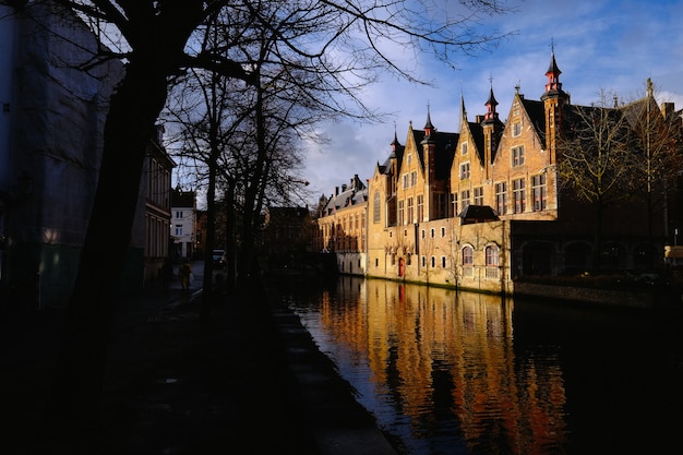 People walking on the sidewalk near a canal in the middle of buildings