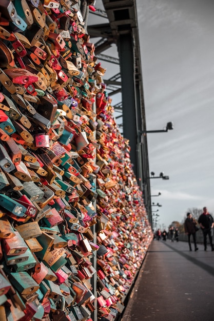 Free photo people walking on sidewalk with assorted-color padlocks on fence