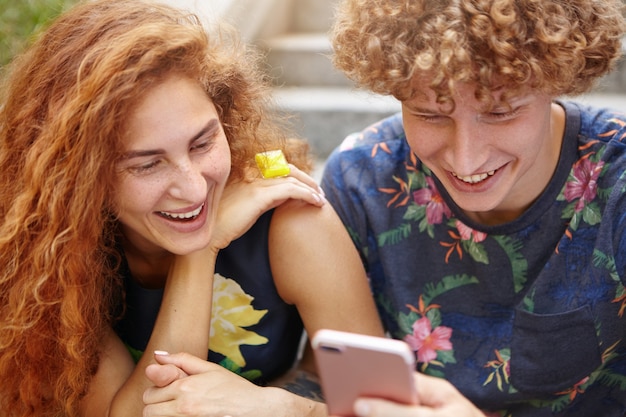 Free photo people watching comedy on smartphone while resting outside sitting at stairs